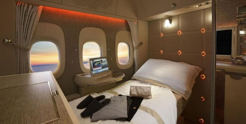 نمایی از سوئیت لوکس Emirates First Class با تخت کامل، طراحی چوبی روشن و فضای خصوصی در هواپیمای A380.