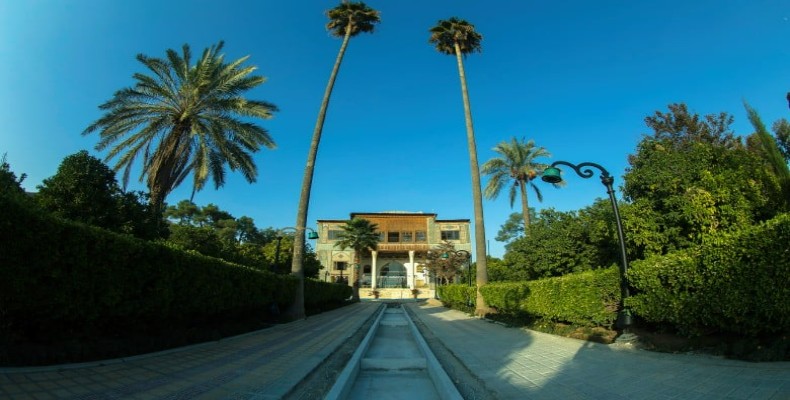 مسیر ورودی باغ دلگشا با نخل‌های بلند و عمارت کلاه‌فرنگی