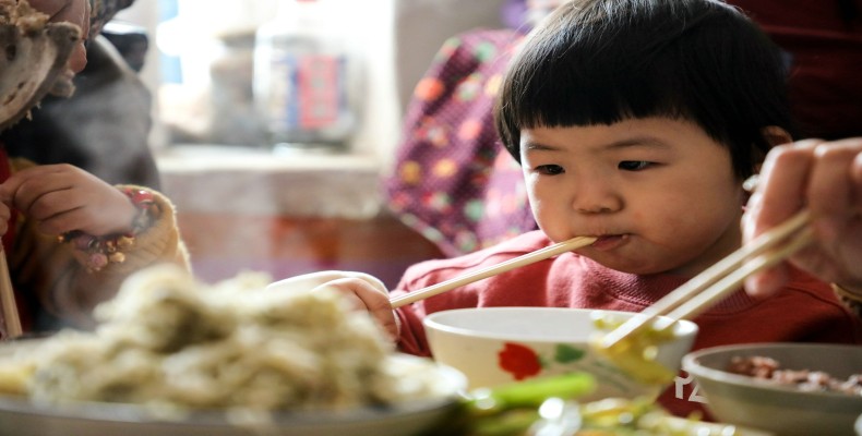 کودک چینی در حال غذا خوردن با چاپستیک؛ نشاندهنده فرهنگ غذایی و قدمت کشور چین