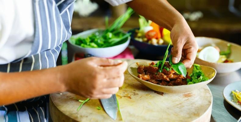 آشپز در حال آماده‌سازی غذا در کلاس آشپزی | تفریحات تابستانی آموزشی