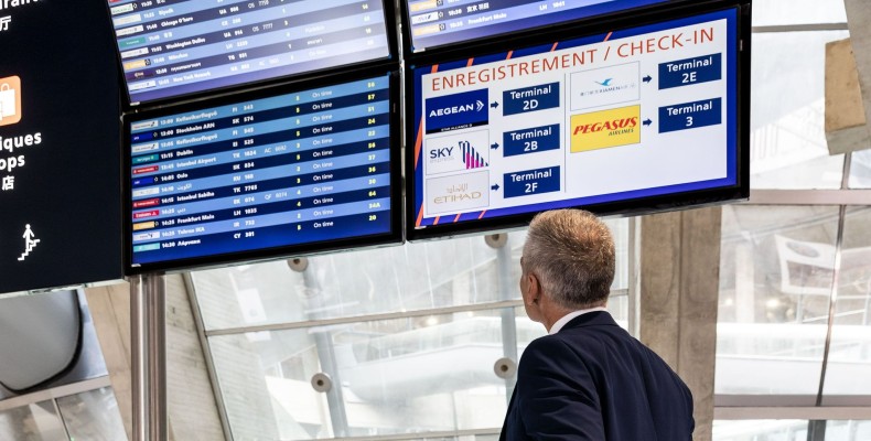 مسافر در حال بررسی مانیتور اطلاعات پرواز برای پیدا کردن گیت فرودگاه