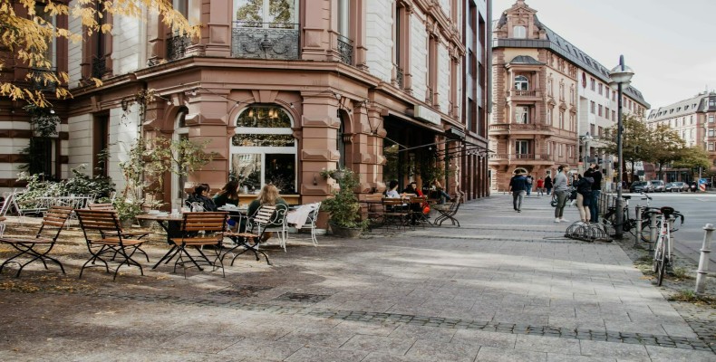 فضای بیرونی کافه Maingold فرانکفورت با میزهای روباز و نمای کلاسیک ساختمان؛ از بهترین کافه های فرانکفورت
