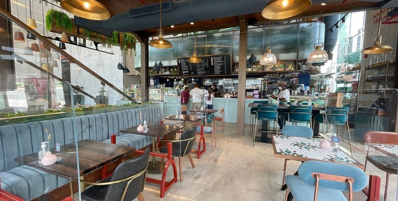 نمای داخلی کافه آشپزخانه الدیسی در جمیرا لیک تاورز با صندلیهای آبی و نور طبیعی