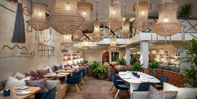 فضای مدیترانهای و روشن رستوران Byblos تورنتو با لوسترهای حصیری و دکور گیاهی